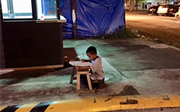 Cậu bé vô gia cư dùng ánh đèn lọt ra từ cửa hàng McDonald's để học bài