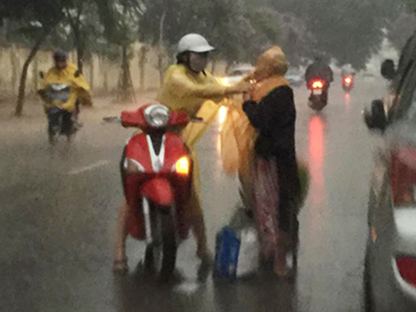Cảm động hình ảnh cô gái dừng xe, mặc áo mưa cho bà cụ không quen