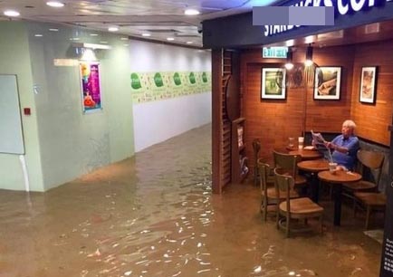 Cụ ông Hồng Kông thảnh thơi ngồi cà phê đọc báo bất chấp lũ lụt