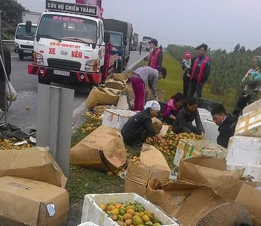 Xe tải bị lật, người dân thu gom hoa quả giúp tài xế