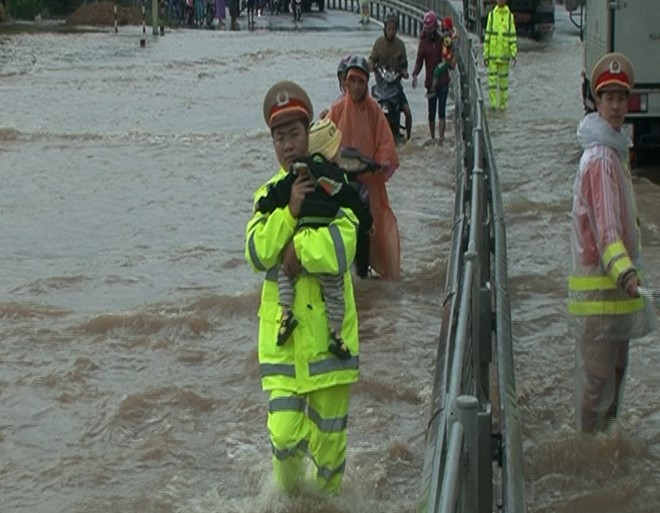 Cảnh sát giao thông bế trẻ qua đoạn nước lụt
