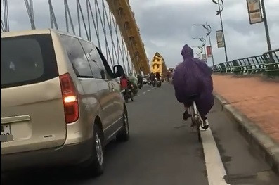 Ô tô đi chậm chắn gió giúp người phụ nữ đạp xe qua cầu ở Đà Nẵng