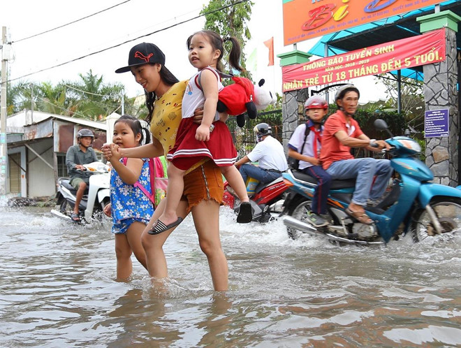 Triều cường Sài Gòn dâng cao, học sinh lội nước theo cha mẹ về nhà
